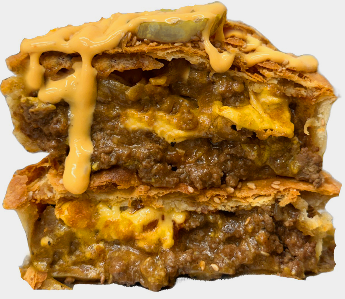 Cheeseburger Pie cut in half with ground beef, onions, American cheese, burger sauce, and pickles